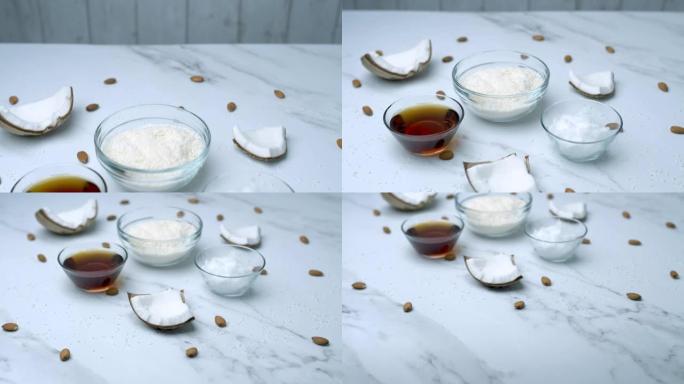 玻璃碗中的特写椰子巧克力配料: 椰蓉、枫糖浆、椰子黄油以及装饰性杏仁坚果、椰子片。突出食品成分的概念