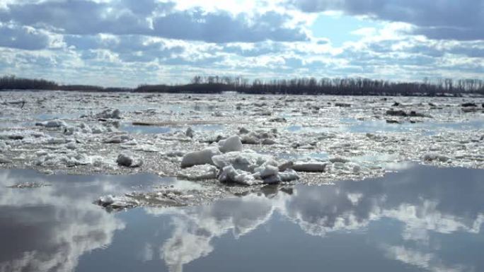 天空中的一组云层在河流的冰体上缓慢地在水中移动。