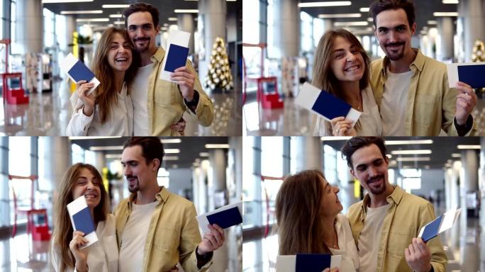 兴奋的高加索夫妇去度假，在机场拿着护照登机牌。挥舞着办理登机手续的护照，对着镜头微笑，拥抱