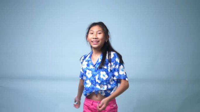 蓝色背景的快乐亚洲女孩跳舞。