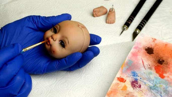 木偶大师用细刷子专心地为洋娃娃涂上空白的嘴唇。