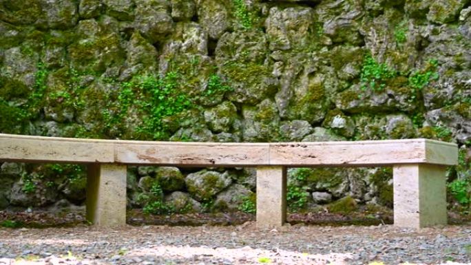 用石头制成的圆形长凳位于公园内，由单个大石头制成的石墙前