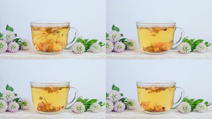 白底玻璃杯中的草药茶，带野花-三叶草花