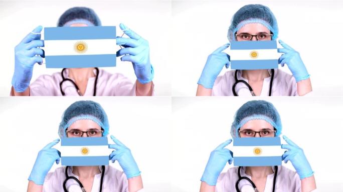 特写。戴眼镜的医生，蓝色医疗帽，手套手持带有阿根廷国旗的医用口罩。医生护理，冠状病毒期间国家保护，全
