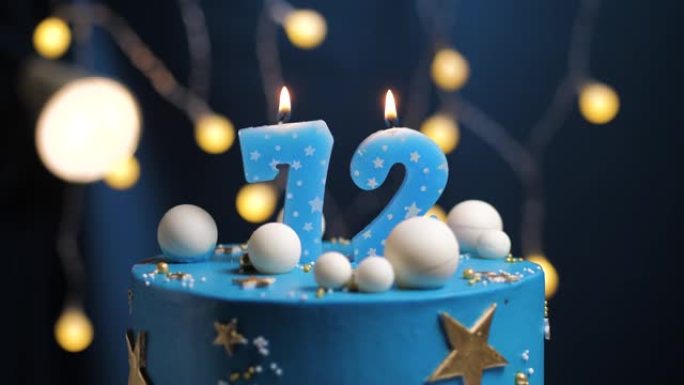 生日蛋糕编号72星星天空和月亮概念，蓝色蜡烛被打火机点燃，然后吹灭。如果需要，请在屏幕右侧复制空间。