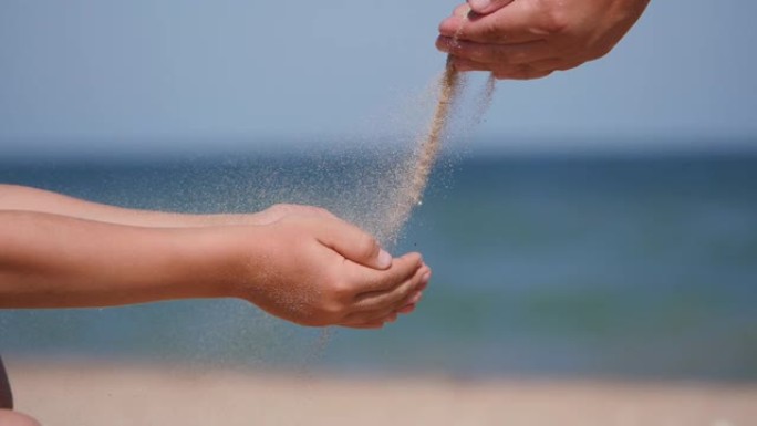 和孩子们一起在海上休息。沙子从手掌倒入孩子的手掌。