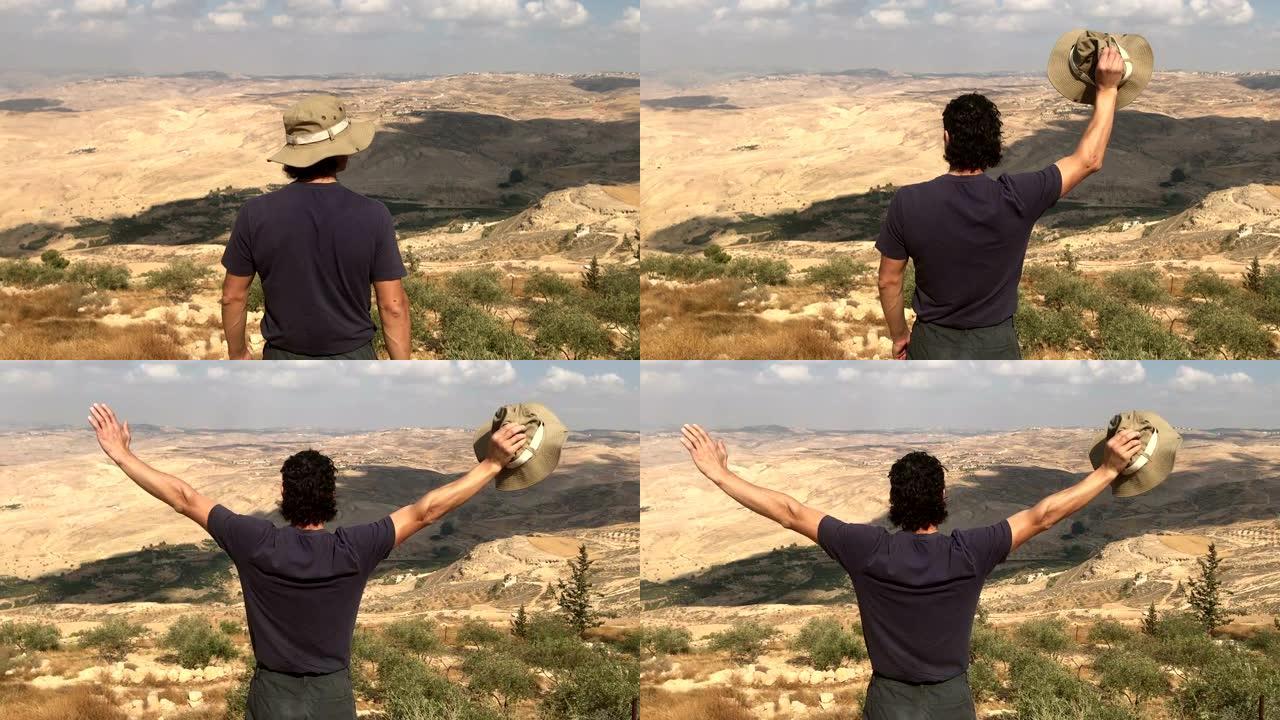 站在山边的人举起手看着美丽的沙漠景观