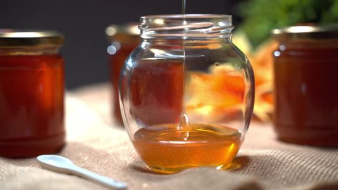 土气生产的蜜罐，浓稠的金色蜂蜜滴在玻璃碗中。甜蜜蜜健康饮食，罐装蜂蜜，药物治疗