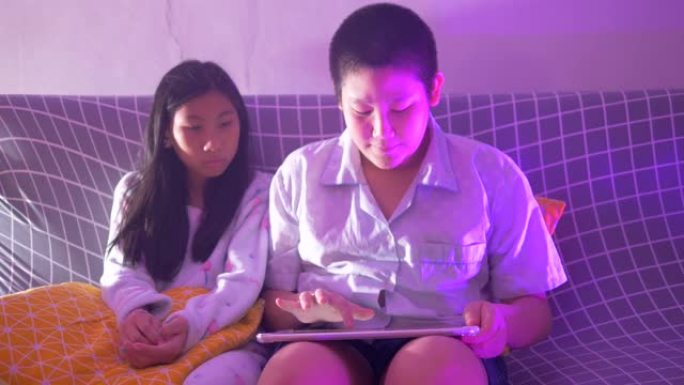 快乐的亚洲青春期男孩使用平板电脑和他的妹妹在线观看视频。