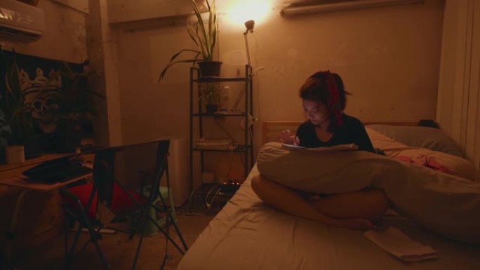 亚洲妇女坐在床上使用智能手机在深夜睡觉前工作，在家工作