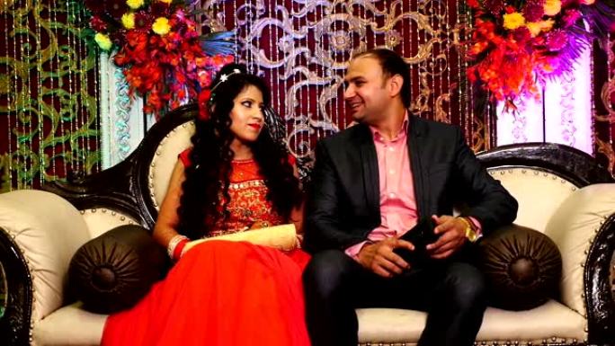 年轻的印度新婚夫妇坐在婚宴大厅的豪华沙发上