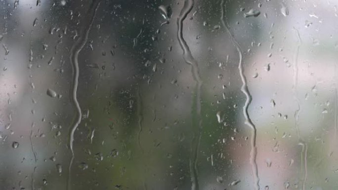 强烈的雨水冲向窗户玻璃并流下来。特写。雨季玻璃背景上的雨滴。4k