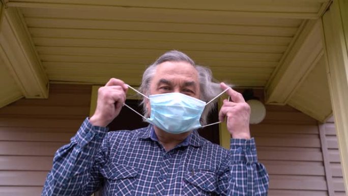 新型冠状病毒肺炎。一位老人站在家门口，摘下防护医用口罩，开心地笑了。