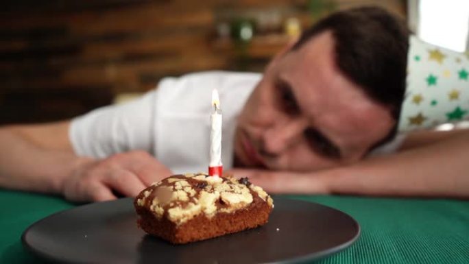 悲伤孤独的年轻人独自庆祝生日，坐在生日蛋糕旁。