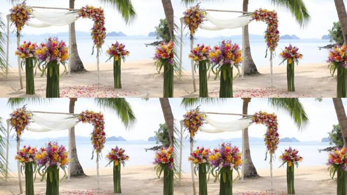 海滩上户外用布和鲜花装饰的婚礼拱门。