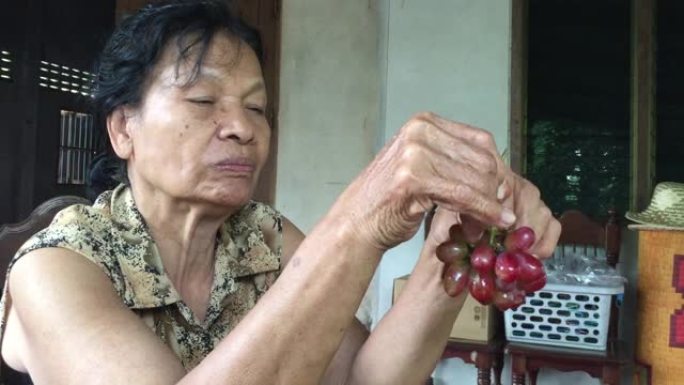 亚洲老年妇女吃红葡萄