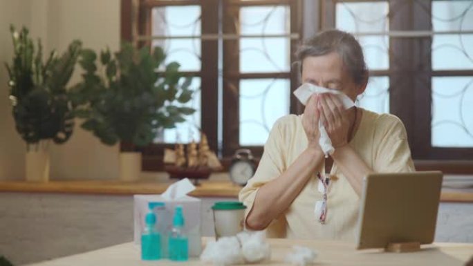 亚洲患病的老年妇女在客厅的组织中打喷嚏