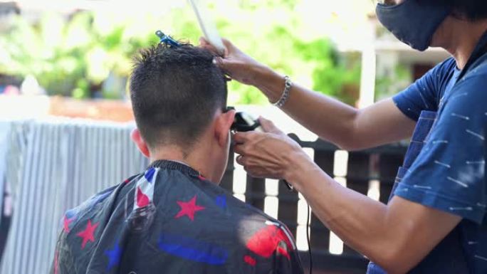 亚洲人在家庭花园理发。在锁定新职业期间学习在线理发师课程。新型冠状病毒肺炎爆发后新的正常生活大流行情