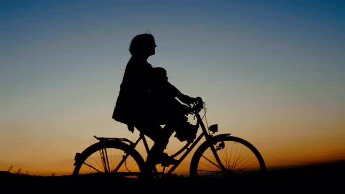 在美丽的夏日夜晚，妈妈和孩子骑自行车的剪影
