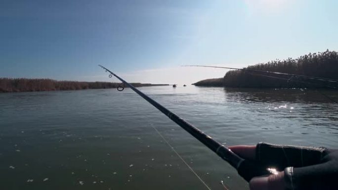 在晴朗的天气下，垂钓者在河上的旋转竿上钓鱼