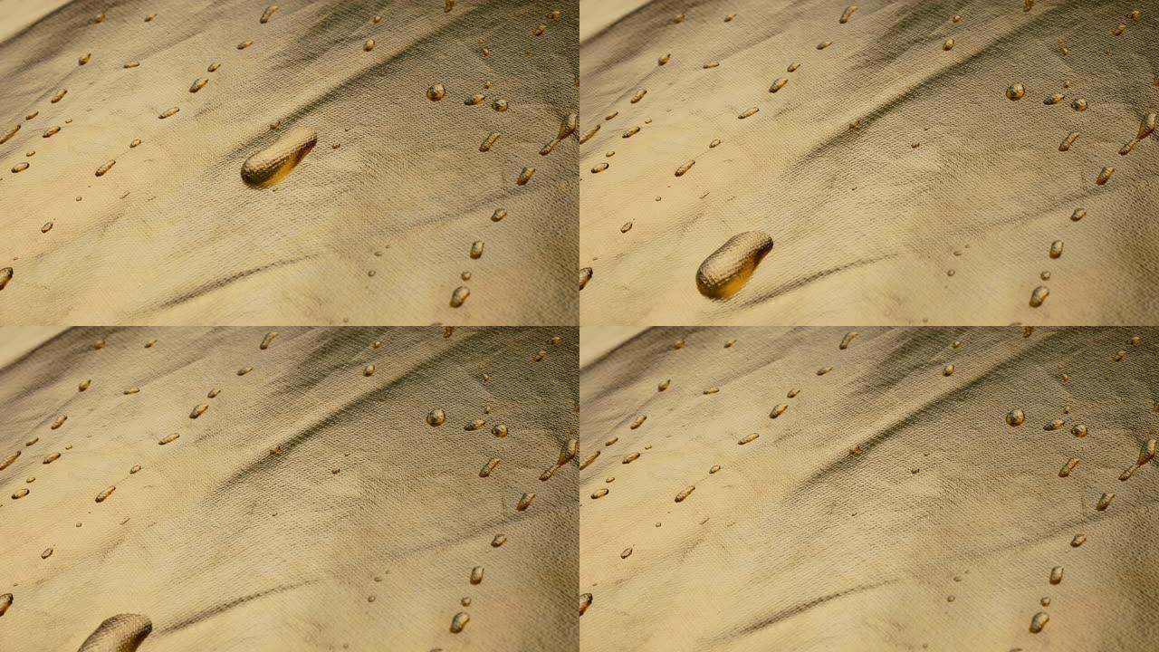 浅金色背景上滚动水滴的Close-up.The运动。抽象纹理。