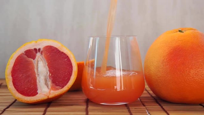 将果汁柑橘维生素汁倒入带有水果的透明玻璃杯中。