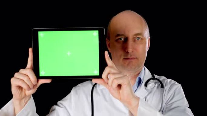 男性医生穿着带听诊器的医疗礼服，手持带chromakey屏幕的平板电脑。医务人员向相机平板电脑展示黑