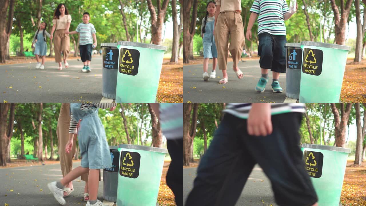 前视图: 周末阳光明媚的日子，亚洲家庭，母亲，兄弟和姐妹在公园的回收站中步行并分离透明塑料瓶作为回收
