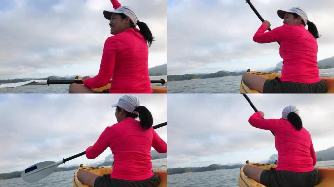 亚洲妇女在早晨的热带大湖中划皮划艇并向朋友挥手。放松运动