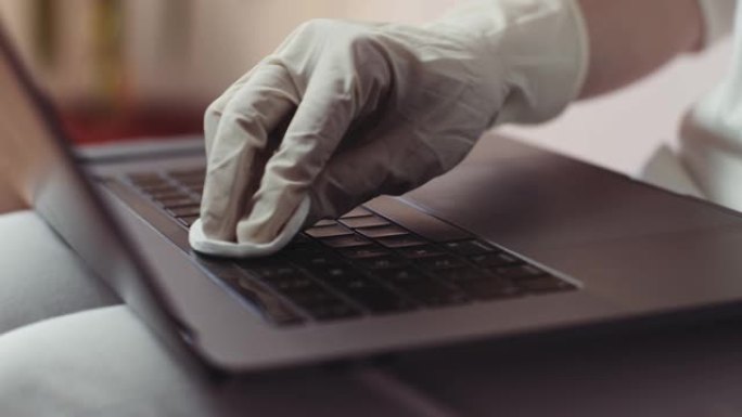 使用抗菌湿巾消毒笔记本电脑库存视频的女人的手戴手套的特写视图