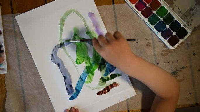 4岁的小男孩在白色床单上画水彩画