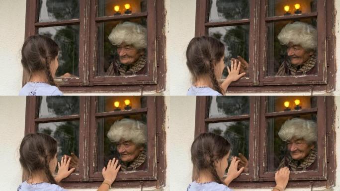 小女孩在大流行期间通过窗户拜访祖母