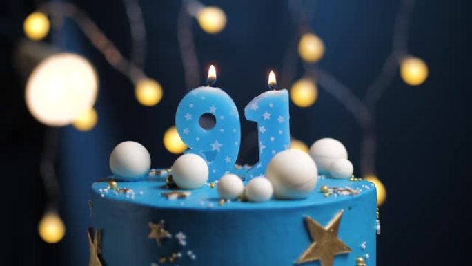 生日蛋糕编号91星星天空和月亮概念，蓝色蜡烛被打火机点燃，然后吹灭。如果需要，请在屏幕右侧复制空间。