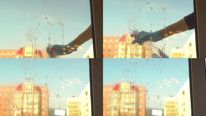 戴着蓝色手套的女人洗窗户，把产品放在玻璃上。