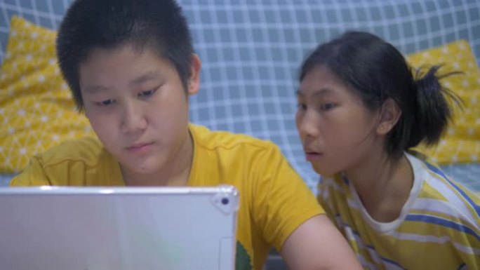 亚洲儿童在家里一起玩平板电脑。
