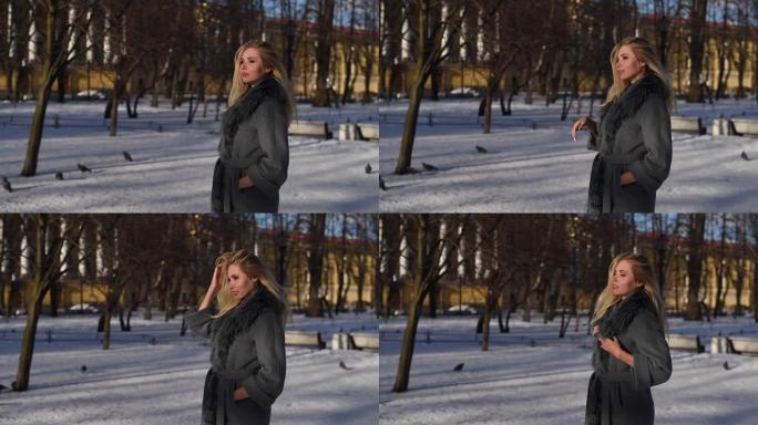 美丽的金发微笑的年轻女子在外面享受冬天的雪和阳光明媚的日子看着相机，微笑，散步的肖像