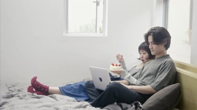 年轻的成年夫妇在圣诞节吃日本草莓海绵蛋糕并进行视频通话