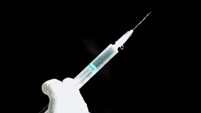 一只手拿着注射器，然后从针头中喷出药液或疫苗