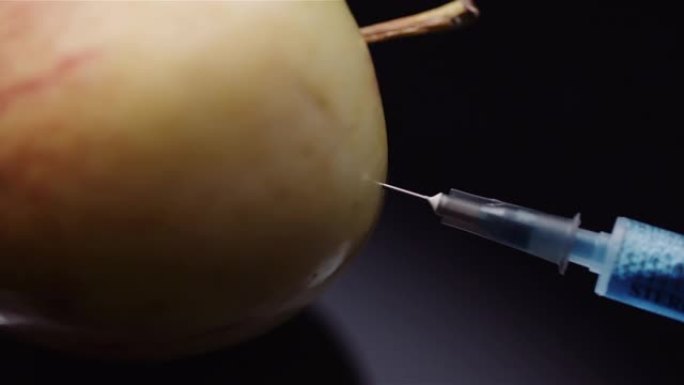 食品转基因-注射器在苹果中注射Liqquid。转基因修饰概念。