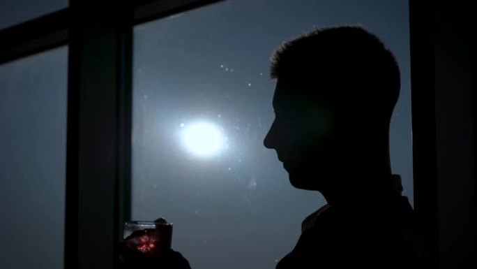 一个男人晚上喝鸡尾酒。在窗口的背景中