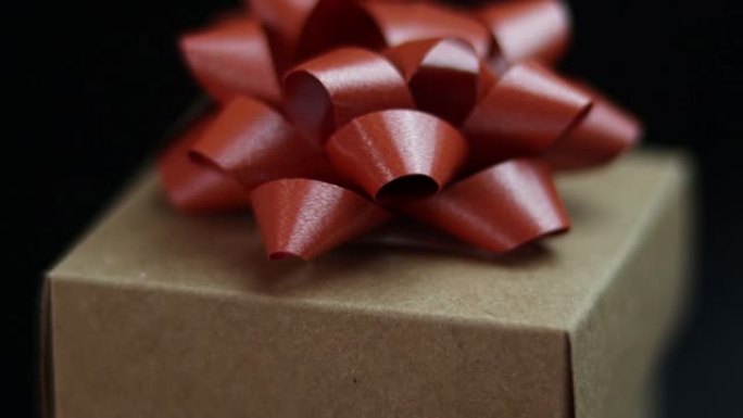 黑色背景特写旋转礼品盒和红丝带的4k视频