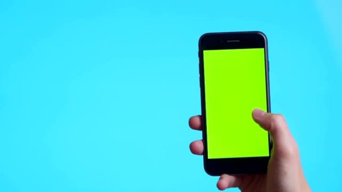 女人手拿着黑色智能手机，绿屏触摸或按下显示，男人使用手机，蓝底色键触摸显示