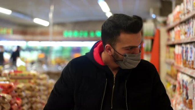 超市里戴着口罩的男子正在寻找消毒剂