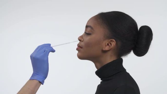 冠状病毒COVID19鼻咽拭子指导。使用植绒的鼻拭子从鼻子内的细胞中收集DNA。一个年轻的非洲裔美国