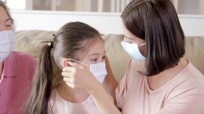 母亲和祖母帮助戴口罩的女儿防止空气污染和新型冠状病毒肺炎冠状病毒