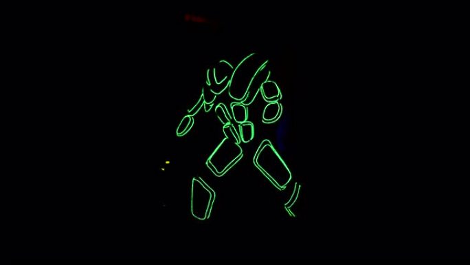 一个穿着电子人霓虹灯服装的人正在黑暗中移动。库存镜头。创意和自我表达概念，不寻常的霓虹条纹服装