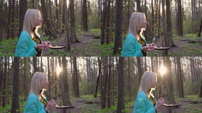 年轻漂亮的金发女郎在森林里野餐。她是一名游客。她手里拿着一个平底锅。