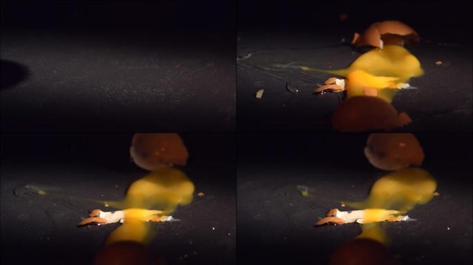 鸡蛋在黑色瓷砖表面以慢动作掉落和破碎。每秒高速1600帧。