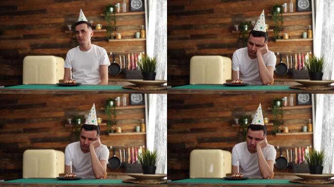 沮丧的年轻人坐在生日蛋糕旁，用悲伤的眼神看着它。