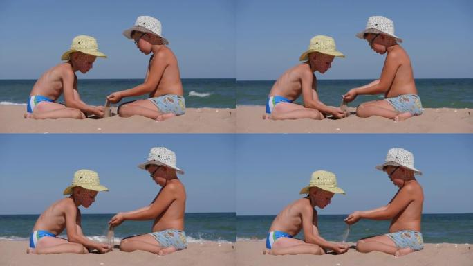 和孩子们一起在海上休息。沙子从手掌倒入孩子的手掌。海边两个戴着帽子的男孩。